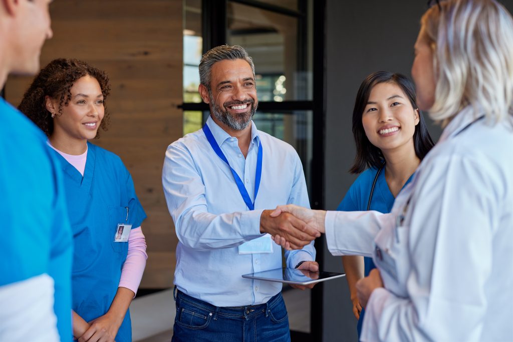 Healthcareaprofessionals greeting pharmaceutical representative. Doctors and healthcare team discussing medical advancements with an indian representative. Medical staff collaborating on healthcare solutions and close a deal with a business handshake.